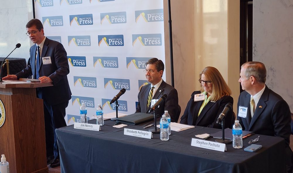 Moderator Derek Redd, standing, talks with three seated panelists: Jim Nemitz, Elizabeth Pellegrin and Stephen Pachuta. 