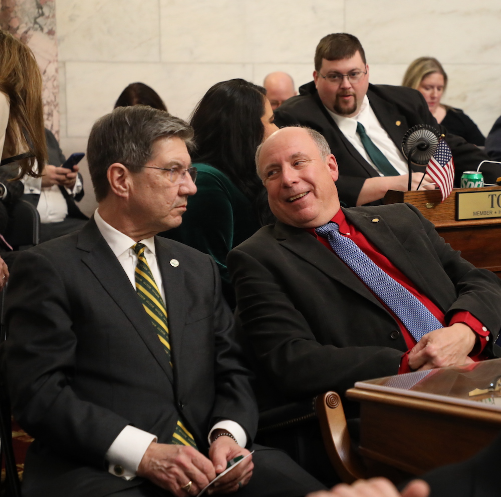 Two men talk while seated at the State Capitol.  