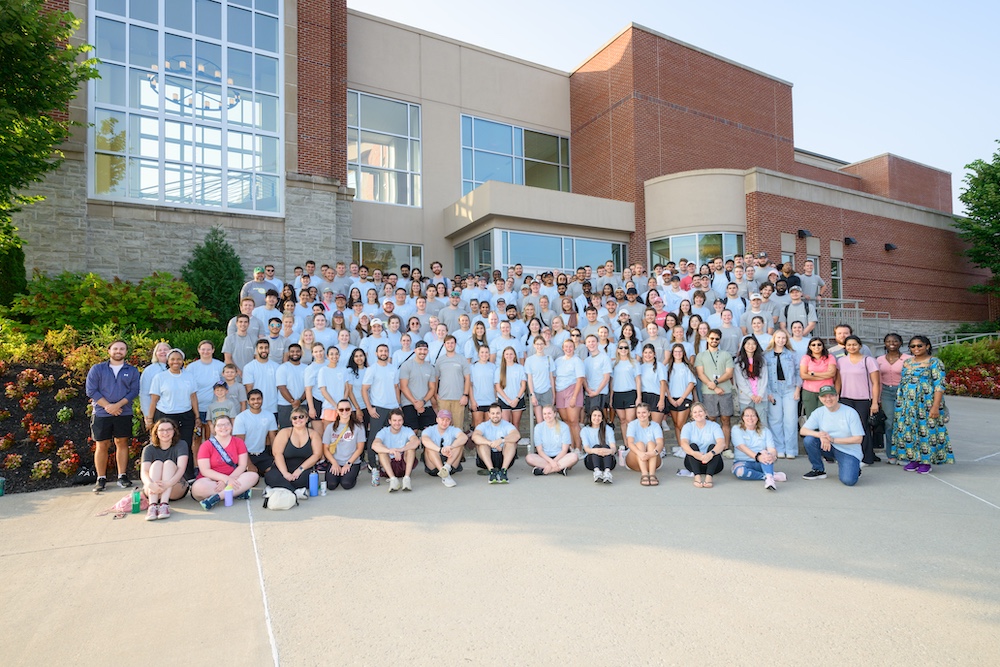 Large group of people pose on steps in front of a building. 