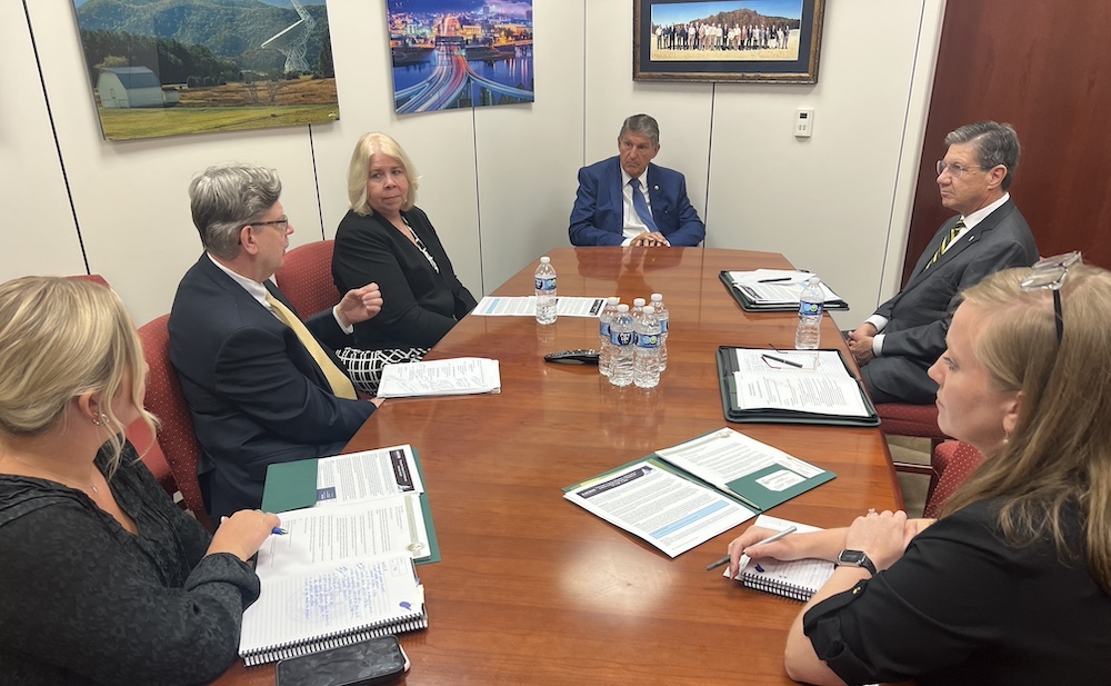 Six men and women sit around a table talking