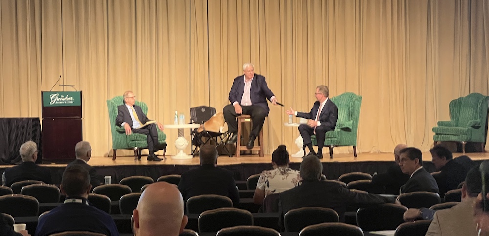 Three men sit on a stage. 