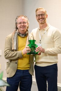 Two men stand togther with an award.