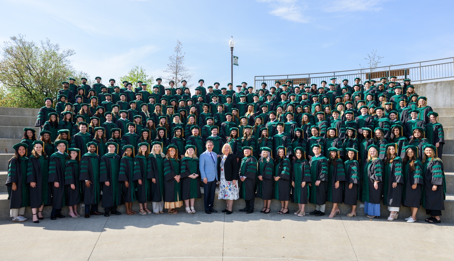 Large group of people in gaps and gowns on steps.