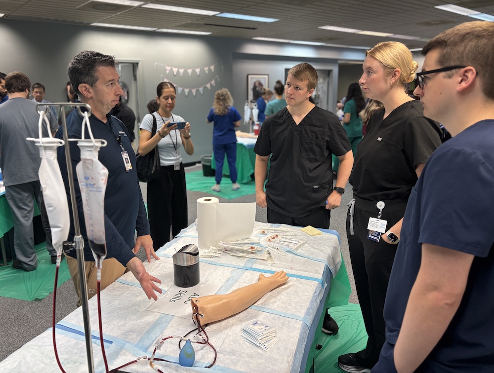 five people stand around a medical table