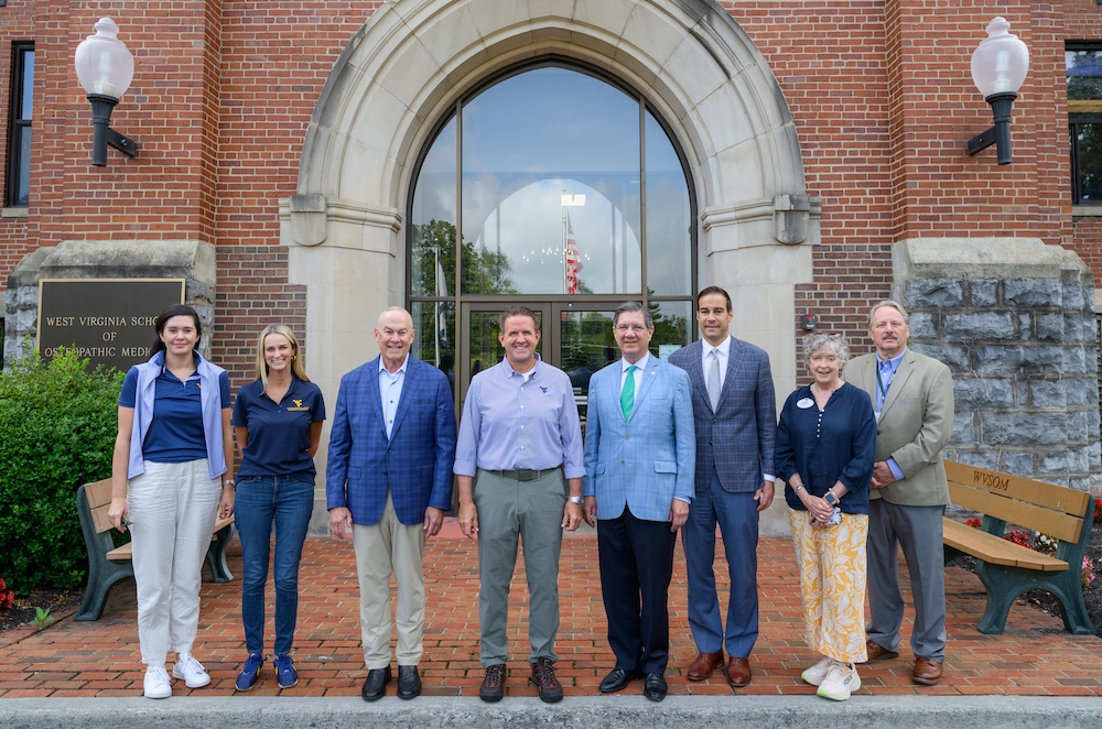 Eight people stand in a line in front of a building.