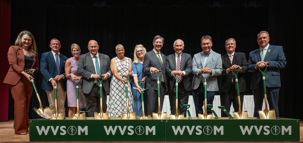 11 people stand in a line with shovels