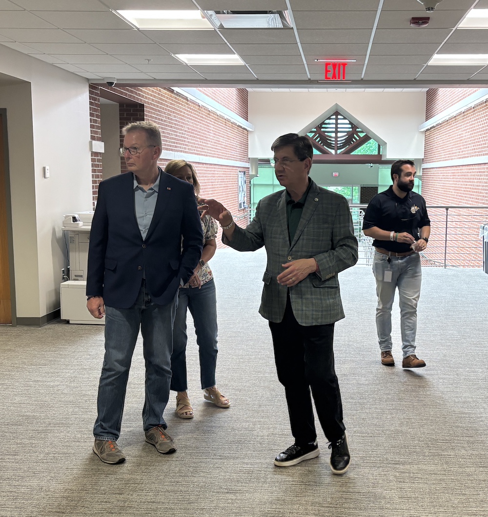 Three men and a woman walk in a hallway