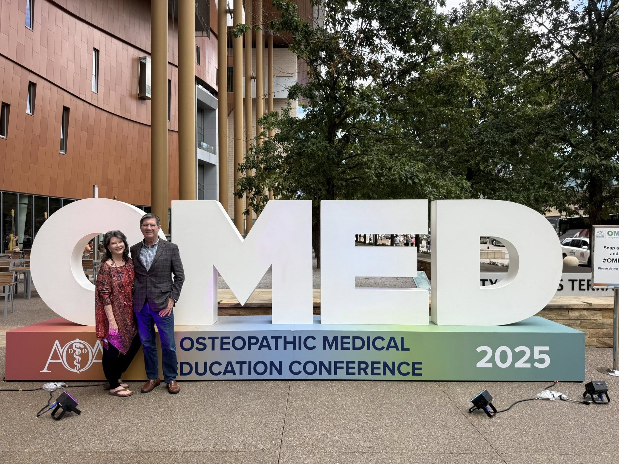 Woman and a man stand in front of a sign