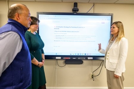 Man and two women look at display screen