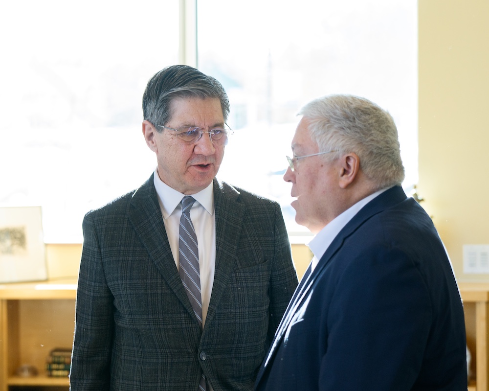 two men stand and talk