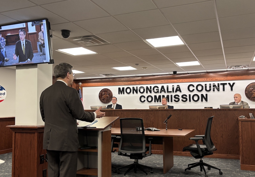 Man stands and talks to three men sitting 