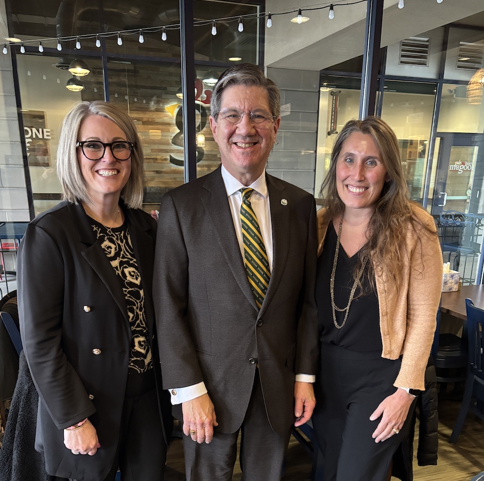 Two women and man stand together. 
