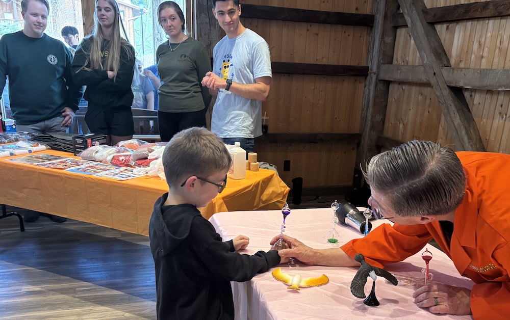 Man talks with child as four people watch in the background.