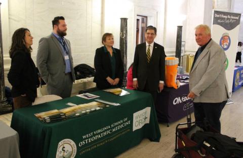 Five people hold a conversation across a display table. 