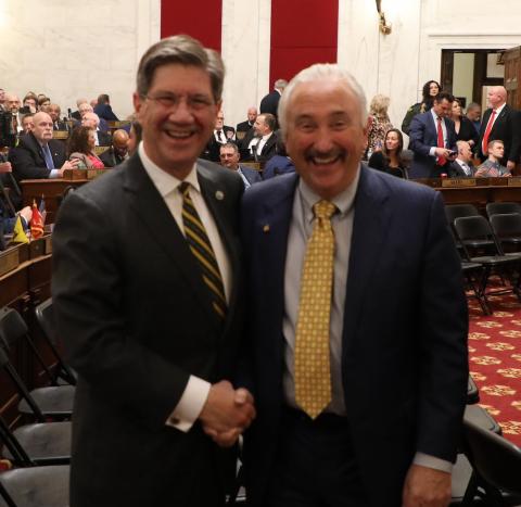 Two men shake hands will standing together. 