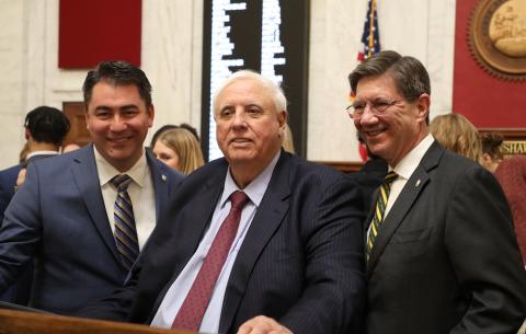 Three men stand shoulder to shoulder to pose for a photo. 