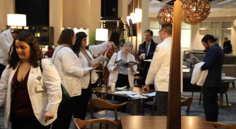 Large group of men and women moving around in a hotel lobby.