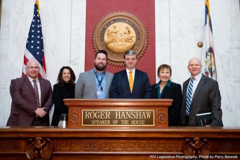 Six people stand around a podium