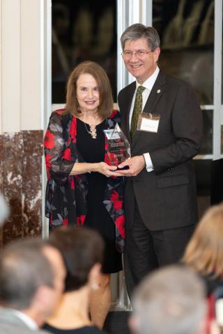 Woman and a man stand at a podium with an award