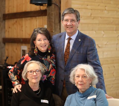 Man and woman standing behind two women seated. 