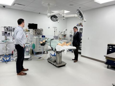 Two men stand in an operating room looking at table.