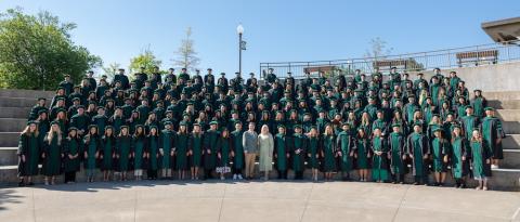 Rows of people in college gowns standing on steps.