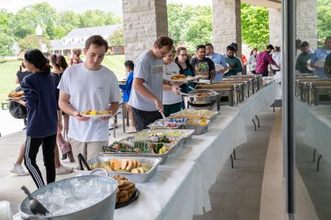 People in a outdoor buffet line. 