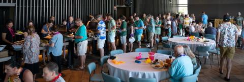 Long line of people getting food at a buffet line.