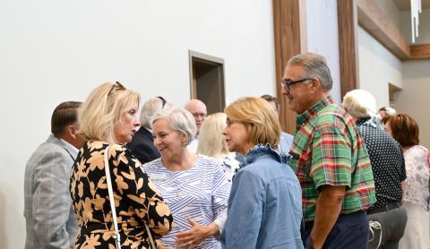 A crowd of people stand and talk
