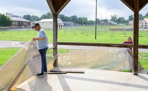 Man and a woman put up a banner at a fair grounds area.