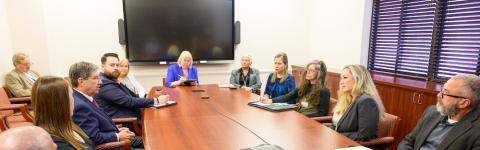 group of people sit around a large table and talk