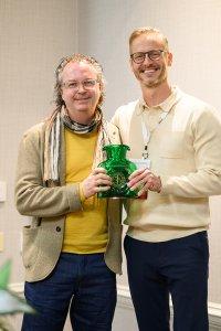 Two men stand togther with an award.