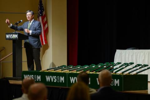 Man stands at a podium near a line of shovels