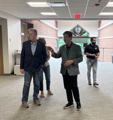 Three men and a woman walk in a hallway