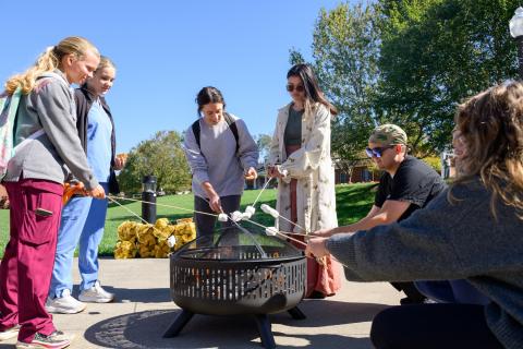 several people stand around a fire pit