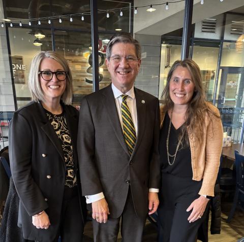 Two women and man stand together. 