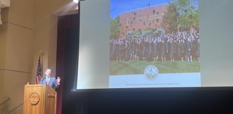 Man stands at podium next to large screen