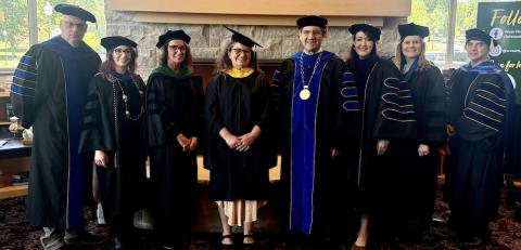 Eight people stand in line before taking the stage as the WVSOM 2026  Master of Science in Biomedical Sciences graduation.