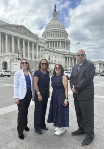 three women and a man stand in front of the nation's capitol