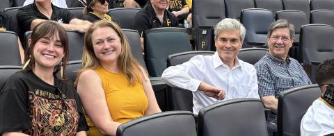 Four people - two women and two men - sit in stadium seats