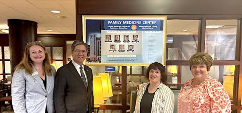 four people line up in front of a sign