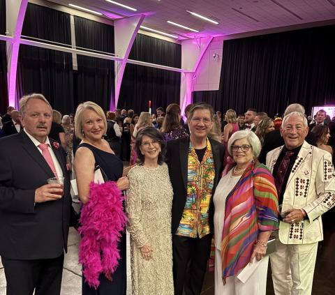 six people dressed for a party stand in line in a ballroom