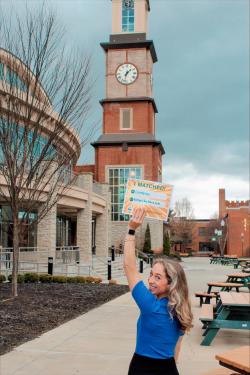 Woman holds up sign in front of a building and clock tower